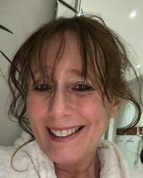 Nicky, smiling, wrapped in a white robe