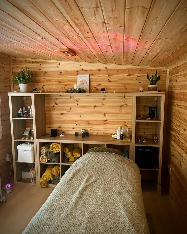 Inside the garden room: the treatment couch, pine walls and shelves of towels and products
