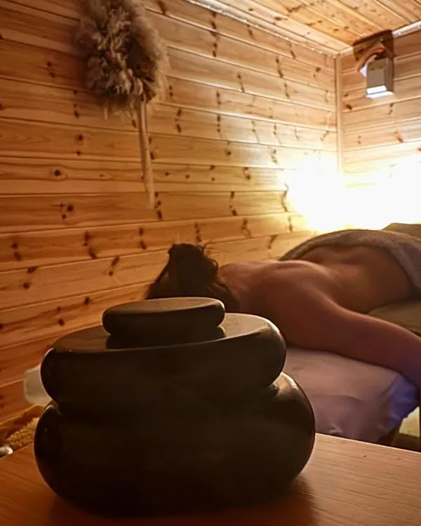 A client relaxing on the treatment couch, with warm massage stones in the foreground